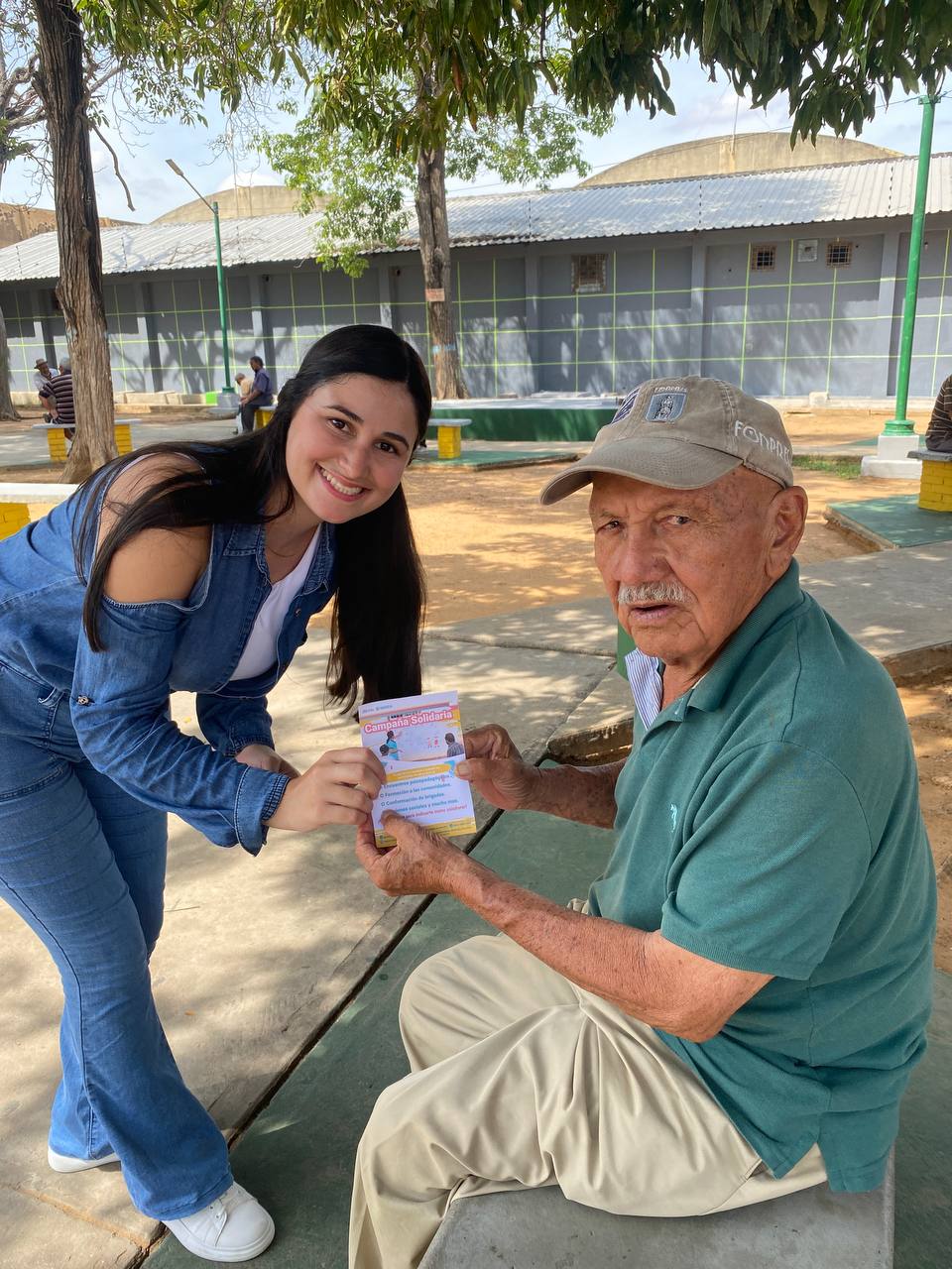 man wearing a black jacket, white shirt, blue jeans, and brown boots, playing a white electric guitar while sitting on an amp